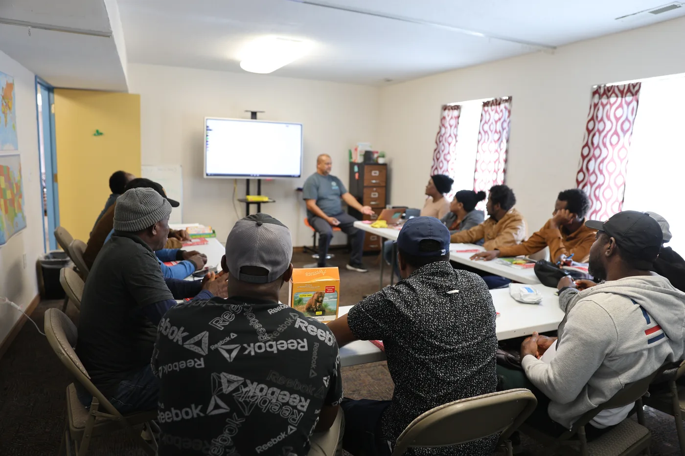 Adult English learners in a CNMC classroom with a world map on the wall