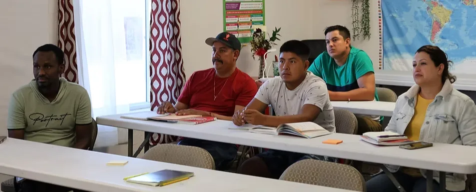 Adult students seated at tables during an EAL class at CNMC