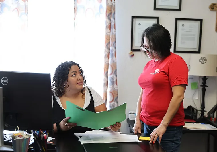 Two CNMC staff members reviewing documents at the immigration services desk